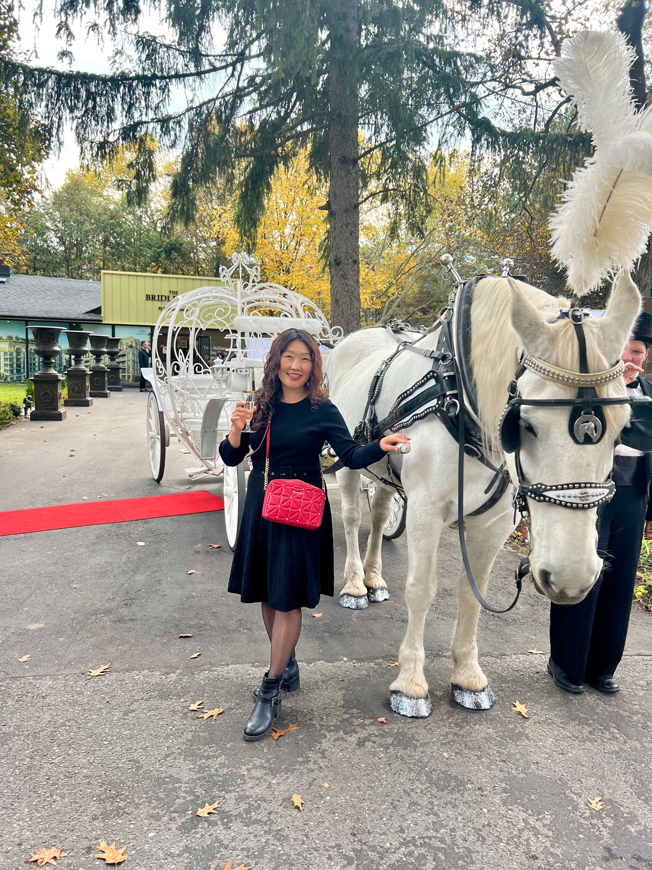Sun Kim at The Bridle Estates grand opening by a white horse-drawn carriage